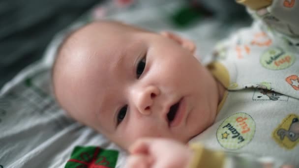 平静地躺在床上的小宝宝 甜美的婴儿张开嘴 在镜头前挥动着拳头 靠近点 — 图库视频影像