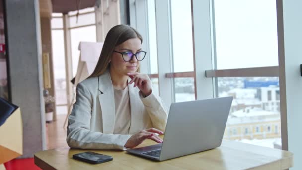 在灯塔办公室工作的积极的年轻女性 迷人的长发女士戴着眼镜在笔记本电脑上上网 — 图库视频影像