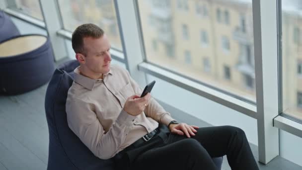 Középkorú Férfi Babzsák Székben Egy Telefont Tart Ember Örül Üzenetnek — Stock videók