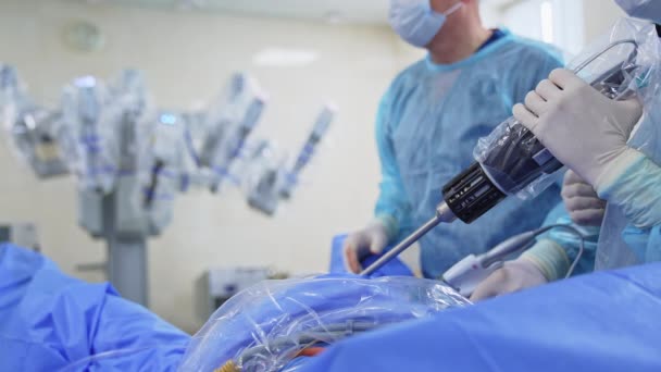 手術における近代的な技術機器の使用 医師の手は 患者に付着した巨大な長い楽器を保持します ブラーレッド バックドロップ — ストック動画