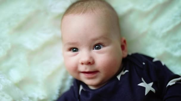 漂亮的男婴 两颊丰满红润 仰卧在床上 可爱的幼儿甜美地打呵欠的脸 靠近点 — 图库视频影像