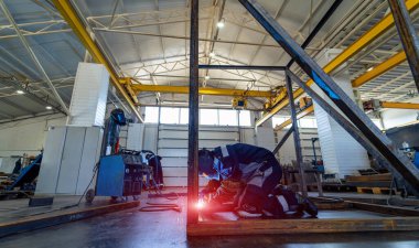 Metal yapıların üretimi için fabrikada çalışan bir adam.