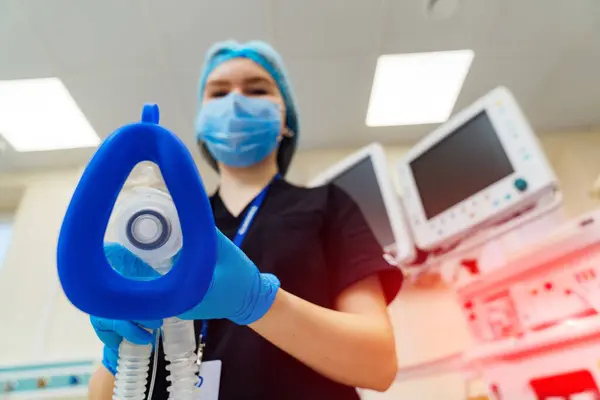 Nurse holds ventilator in her hands.