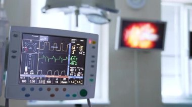 Operasyon sırasında operasyonel tiyatroda çalışan ekipmanlar. Önplanda hayati parametreleri olan bir ekran. Görüntü arkaplanındaki ameliyat sürecini görüntüle.