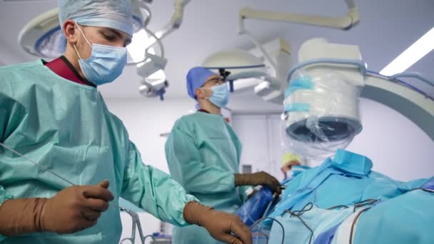 Mężczyzna Asystent Podaje Długą Metalową Igłę Głównemu Chirurgowi Lekarz Tle — Wideo stockowe
