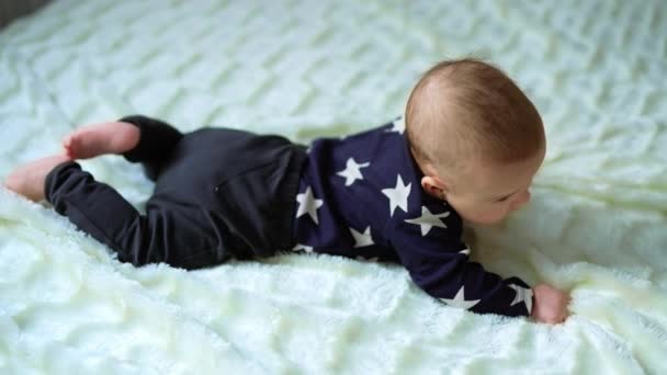 胃の上に横たわっている可愛い小さな赤ちゃん かわいい小さな男の子が周りを見回して 彼の小さな足を動かします 上からの眺め — ストック動画