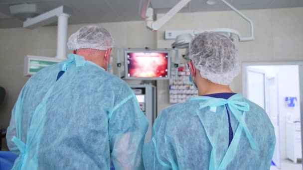 Два Лікарі Стоять Спиною Камери Оперують Пацієнтом Хірурги Співпрацюють Спостерігають — стокове відео