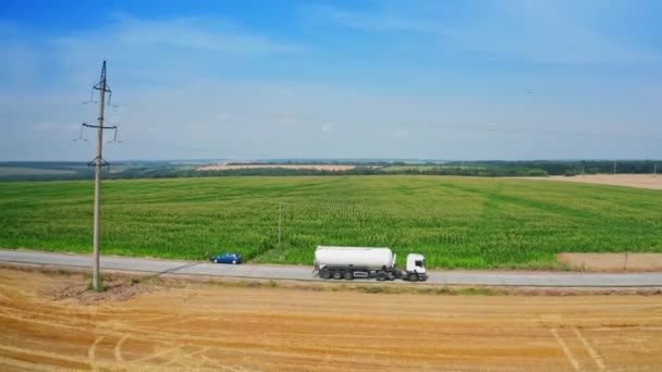 農地やトラックを横断する道路 カットフィールドによって干し草バレルに乗って積まれたトラクター トップビュー — ストック動画