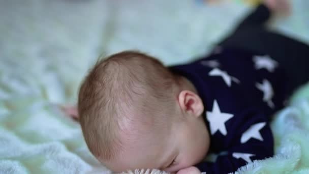 美しい白人幼児がベッドの上に横たわり 頭を上げています かわいい赤ん坊は時々ベッドの上に頭を休ませている クローズアップ — ストック動画