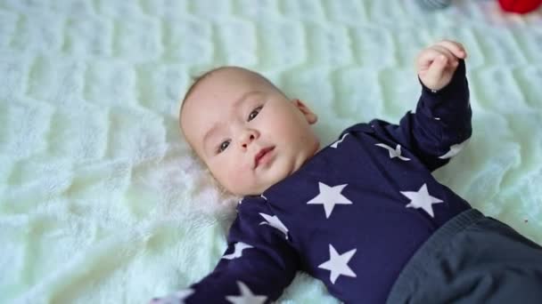身穿深色睡衣的男婴躺在床上 从上面看孩子平平静静躺在白色的背景上 靠近点 — 图库视频影像