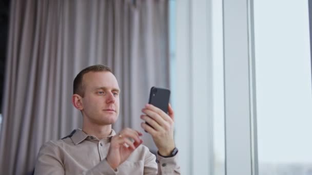 Улыбающийся Молодой Человек Смотрит Телефон Перед Собой Работник Мужчина Отдыхает — стоковое видео