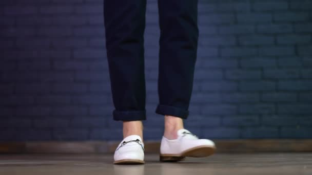 モデルの白い靴のデモンストレーション 新しい快適な履物で背中と前後にねじれる女性の足 ブルーレンガバックドロップ — ストック動画