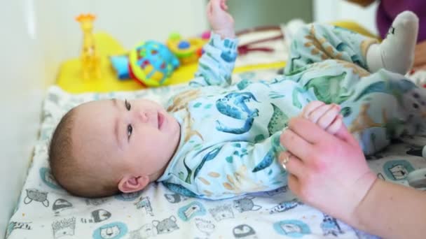 小児科医の手は赤ちゃんの手を握っています かわいい子供は医者に見え 微笑み返した クローズアップ サイドビュー — ストック動画