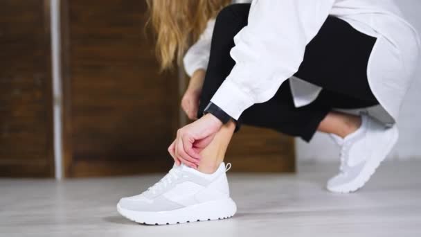 女模展示了新的白色运动鞋 女士把鞋带绑在鞋袜上 靠近点模糊的背景 — 图库视频影像