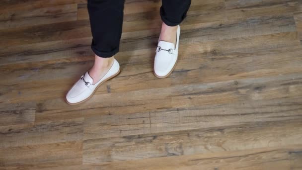 白い快適なカジュアルな靴のデモンストレーション 木製の床の背景に新しい靴を着たレディースモデル 上からの眺め — ストック動画