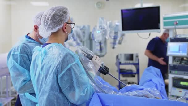 Νεώτερος Άντρας Χειρουργός Κρατά Μακριά Συσκευή Που Συνδέεται Έναν Ασθενή — Αρχείο Βίντεο