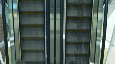 Merdivenler inip çıkarken alışveriş merkezinde yürüyen merdiven. Kız arkadaşı, erkek arkadaşıyla karşıdaki merdivenlerde buluşuyor. Yukarıdan görüntüle.