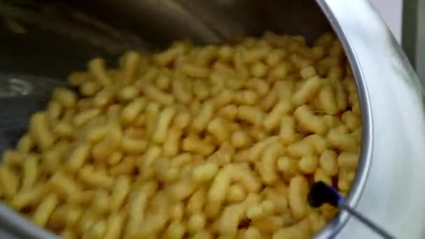 美味的酥脆小吃 上面涂满了甜糖浆 玉米棒旋转在食品制造厂的金属罐中 靠近点 — 图库视频影像