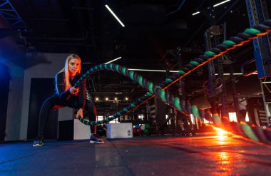 Atletik genç bayan spor salonundaki iplerle çalışıyor..