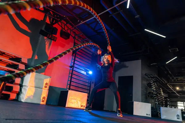 Young athletic man with battle rope battle ropes exercise in the fitness gym. CrossFit concept.