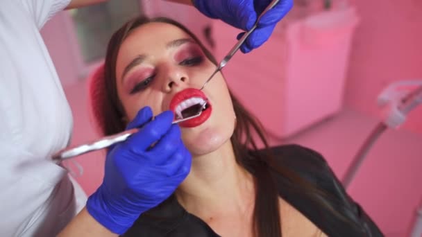 歯科医の手は 吸血鬼の歯を調べる レディ ヴァンパイア 歯医者の検査で黒い服を着た クローズアップ — ストック動画