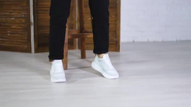 Bağcıklı, yeni, rahat bir spor ayakkabıyla dans etmek. Kadın model, şık spor ayakkabılarını göstermek için atlıyor..