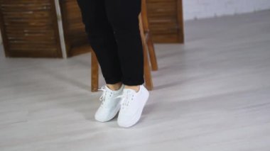 Rahat beyaz ayakkabıların içine atlayan bir model. Havalı spor ayakkabılarını göstermek için dönen ve zıplayan bir kadın..
