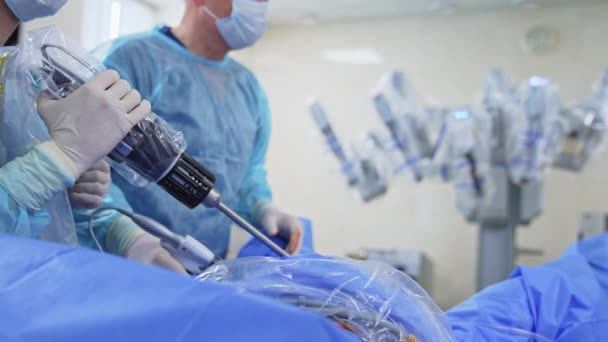 患者に適用される外科医の手の高度なロボット機器 ドクターはそれを素早く動かす装置を使用しています バックドロップのダ ヴィンチロボット — ストック動画