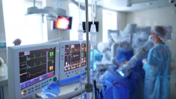 現代の手術では2つのスクリーンが使われています 患者の重要なパラメータを表示するモニター ドクターは後ろにロボット装置に立っています — ストック動画