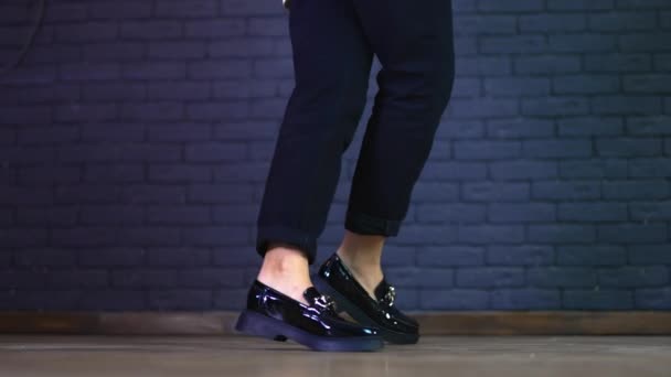 黒いジーンズの少女は 銀の鎖の装飾で現代の巨大な靴を示しています 灰色のレンガの壁の背景 — ストック動画