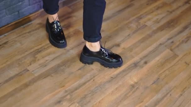 女人穿着黑大号的鞋子 鞋带和拖鞋底 女士靠在蓝色的墙上展示时髦的鞋子 — 图库视频影像