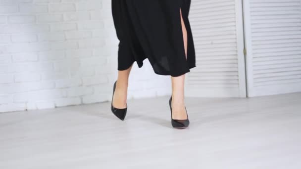 エレガントなクラシックなブラックシューズデモンストレーション 長い黒いスカートの女性は ハイヒールのシュレットの靴を示しています ホワイトバックドロップ — ストック動画