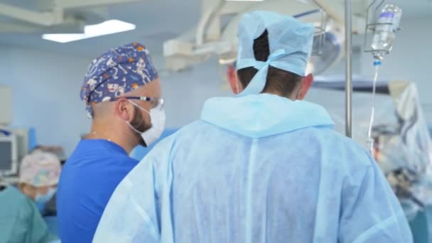 Dwóch Lekarzy Stoi Nad Pacjentem Sali Operacyjnej Rozmawia Personel Pomocniczy — Wideo stockowe