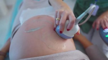 Elinde ultrasonik cihaz tutan bir doktorun eli, bir hastanın karnının üzerinde hareket eder. Kapatın. Ultrason kontrol konsepti.