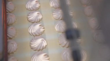 Lezzetli kremalı şekerler konveyör bandında yavaşça ilerliyor. Taze vanilyalı tatlılar makineden çıkıyor. Kapatın. Üst görünüm.