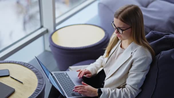 在笔记本电脑上工作的年轻女商人安静下来 坐在椅子上 在大窗户旁边一个舒适的地方做自由职业的职业女性 — 图库视频影像