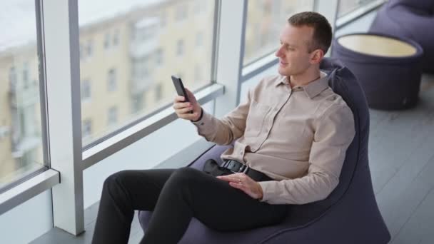 Uvolněný Mladík Sedí Křesle Telefonem Ruce Muž Odpočinek Těší Panorama — Stock video