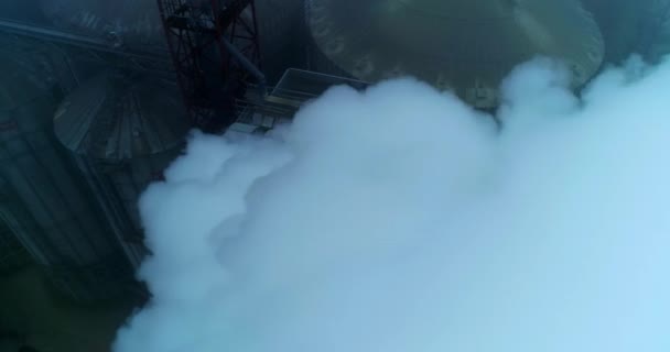五根相连的管子冒着浓浓的白烟 灰色冬日从空中看粮仓综合体房地和油罐 — 图库视频影像