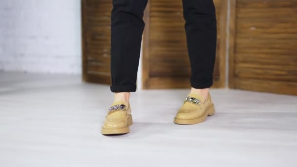 ブラックジーンズを着用した女性モデルのベージュ快適な靴 シルバーチェーン装飾の新しいローファーをデモンストレーション — ストック動画