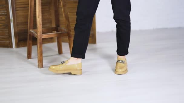 女性はファッショナブルな新しい靴で歩き回ります チェーンデコレーションのプレーンソールのベージュスタイリッシュなフットウェア バックドロップの木製のスツールと折りたたみスクリーン — ストック動画