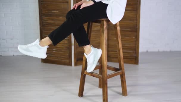 Kobieta Siedzi Wysokim Stołku Wymachując Stopami Białych Trampkach Model Skacze — Wideo stockowe
