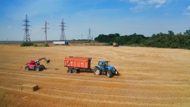 大きな空のトラクターがモウドフィールドで移動します バックドロップで干し草と収穫された小麦の乾燥した農地 — ストック動画