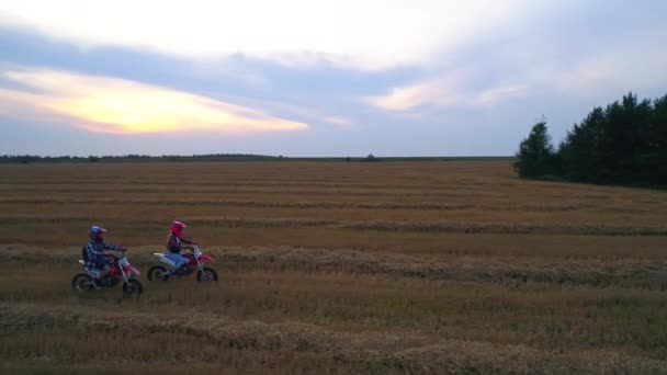 日落时 两个人在田野里骑摩托车 在美丽的农田背景下 在农村度过积极的时光 — 图库视频影像