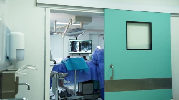 Стоя Открытой Двери Операционного Зала Команда Хирургов Проводит Операцию Пациенту — стоковое видео