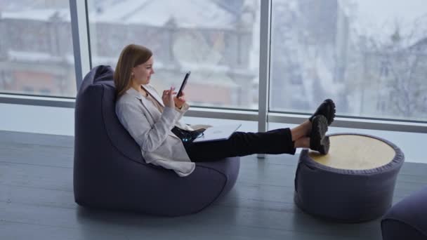 Calma Senhora Relaxada Olha Para Seu Telefone Sentado Cadeira Esticando — Vídeo de Stock