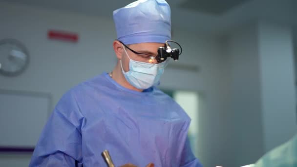 長い金属の外科用具の操作のベテランの外科医 カメラに話しかける医師の肖像画 — ストック動画