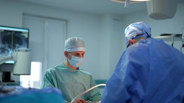 医師は現代の手術室で患者を手術する オペレーショナルシアターを離れて ドアウィンドウでそれを見る — ストック動画