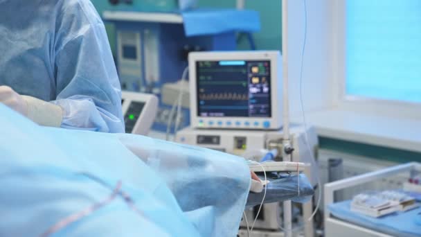 手術中に付属の機器を搭載した患者の手 バックドロップ時に重要なパラメータを備えた作業画面 — ストック動画