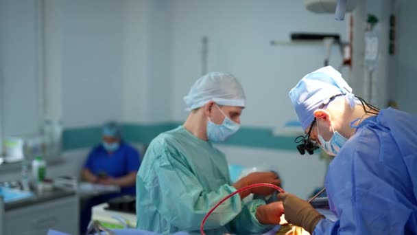 外科医生使用仪器 并将一些物品交给助手 护士背靠背地坐在模糊的地方 — 图库视频影像
