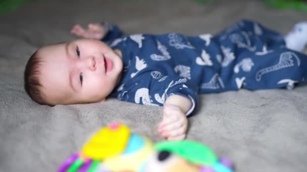 Spokojny Chłopiec Leży Plecach Patrzy Zabawkę Sześciomiesięczne Dziecko Leżące Szarym — Wideo stockowe
